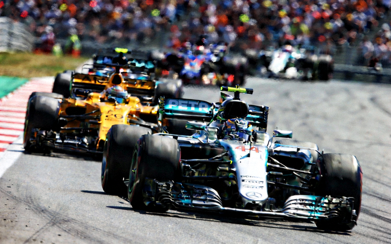 F1大奖赛焦点图 - 多辆F1赛车在直道上并排飞驰，速度感极强，背景是模糊的赛道和观众席